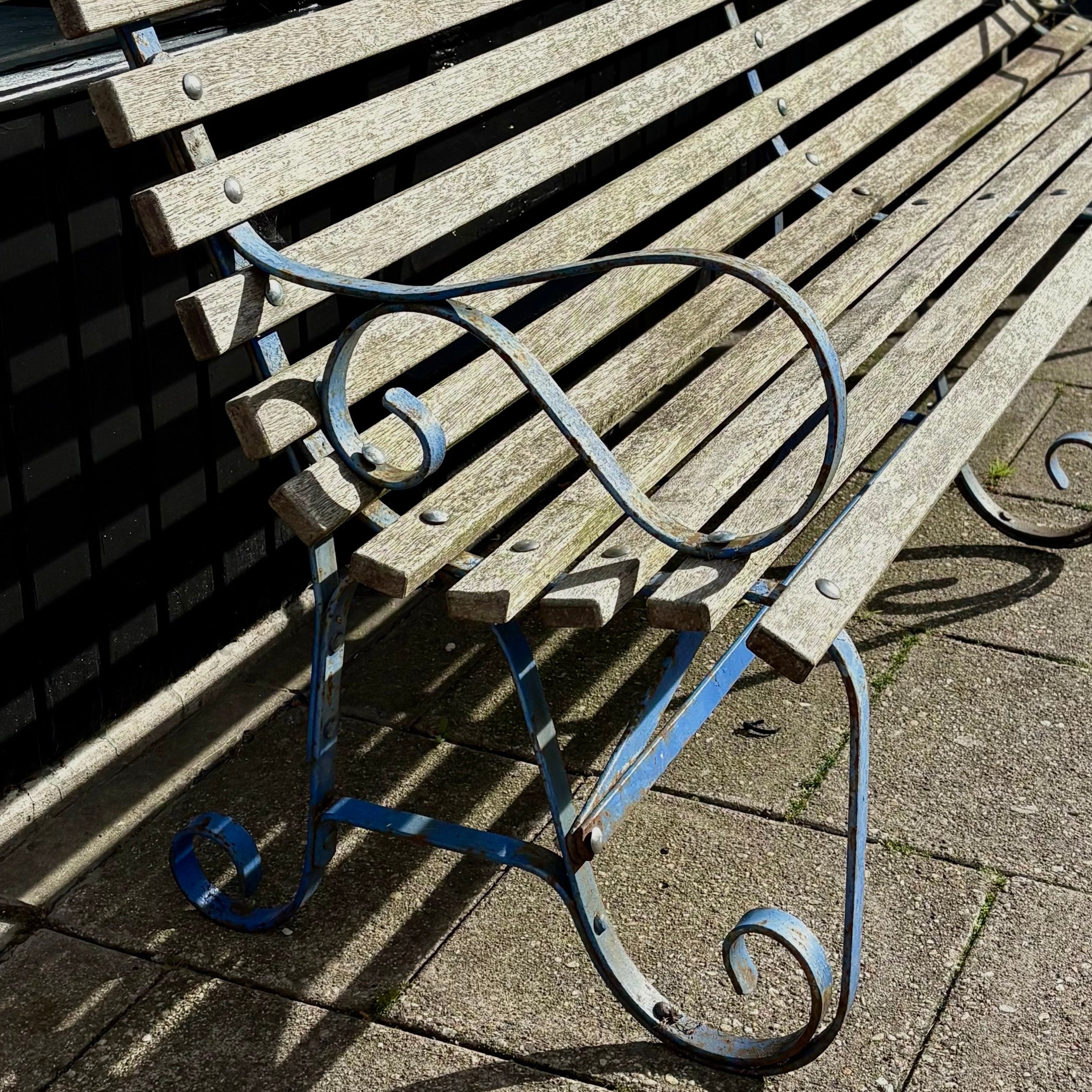 Wooden bench with metal legs on a pavement.